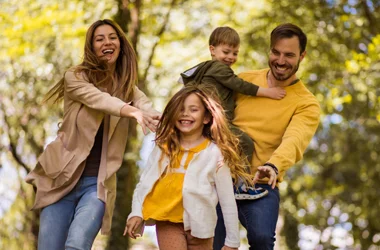 Dentist Vista CA Family Dentistry BOX A mother, father, son, and daughter, laughing during a nature walk in autumn